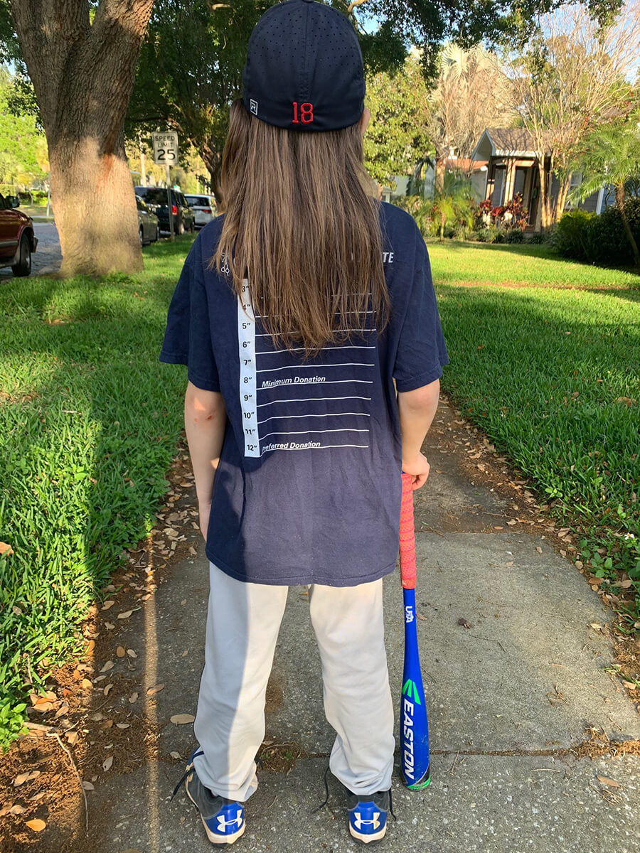 Eli, a long hair in little league, wearing his Great Cut 2024 T-shirt