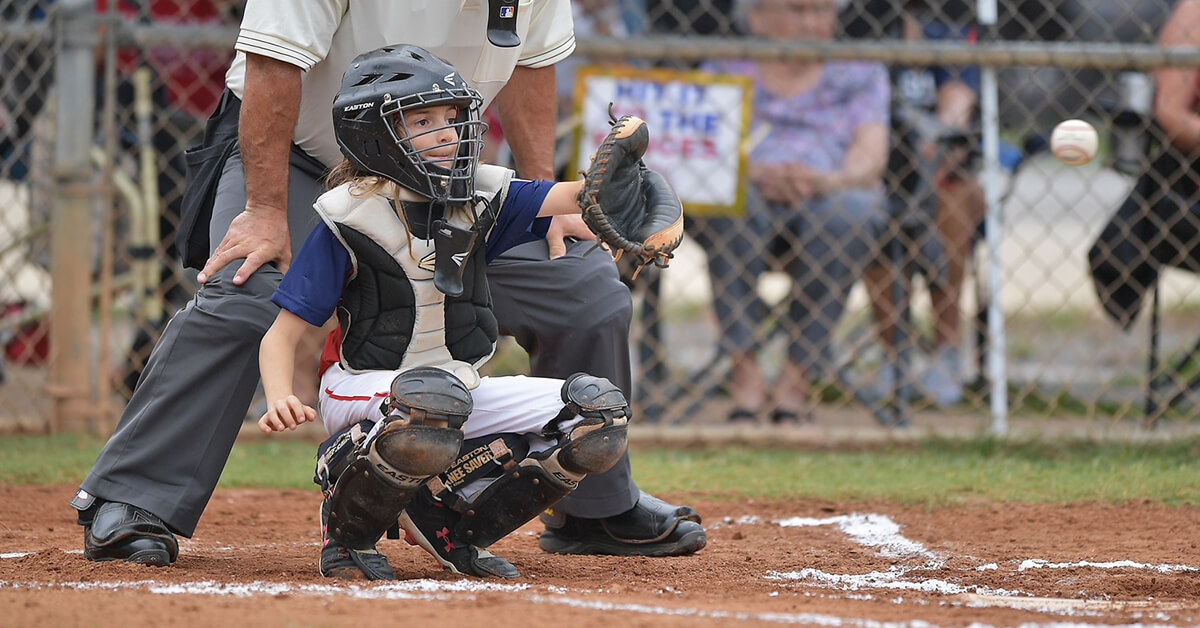 Eli, a long hair in little league, playing catcher