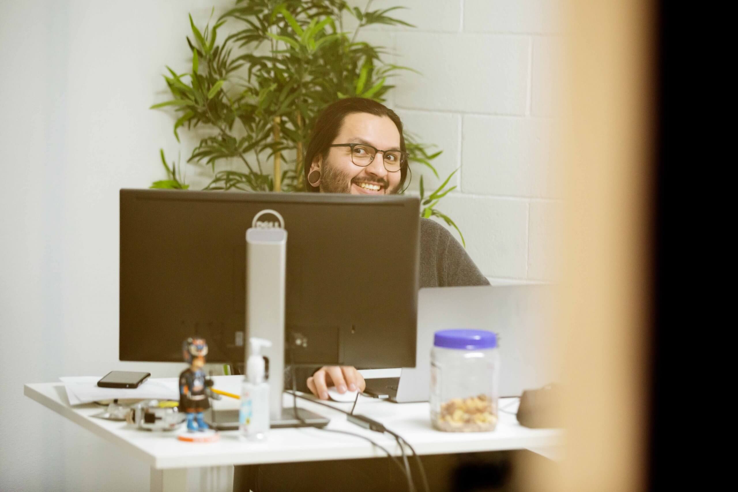 Gustavo smiling behind his desk as he settles in to his new office.