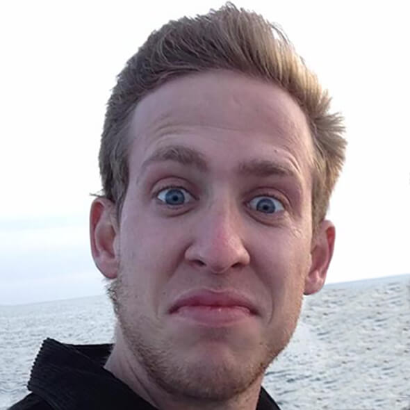 Chuck at 20 years old, hair blowing in the wind as he rides a boat. The wind has blown his hair back, revealing an enviable hairline.