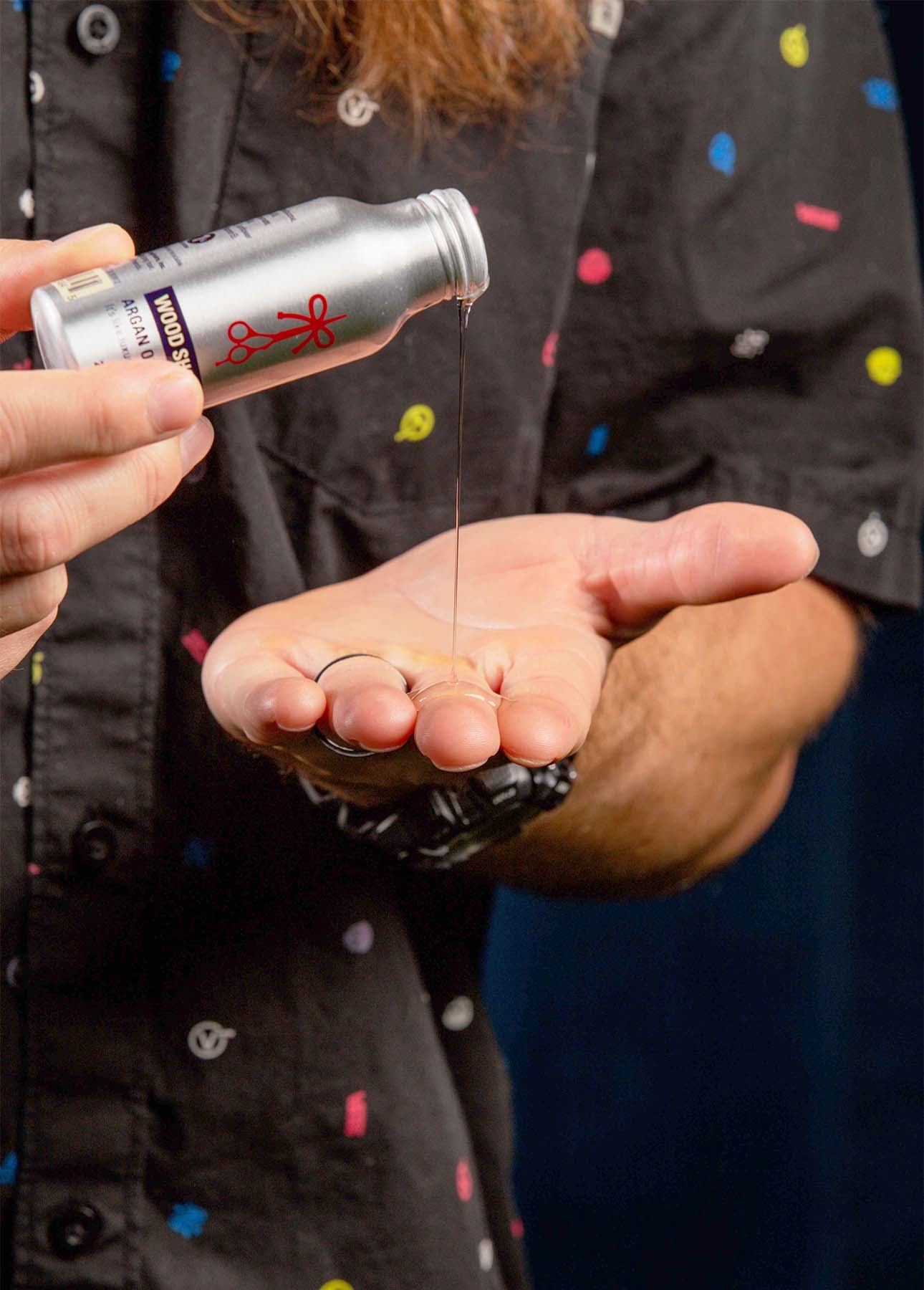 Pouring out wood shop hair serum by the longhairs into a hand