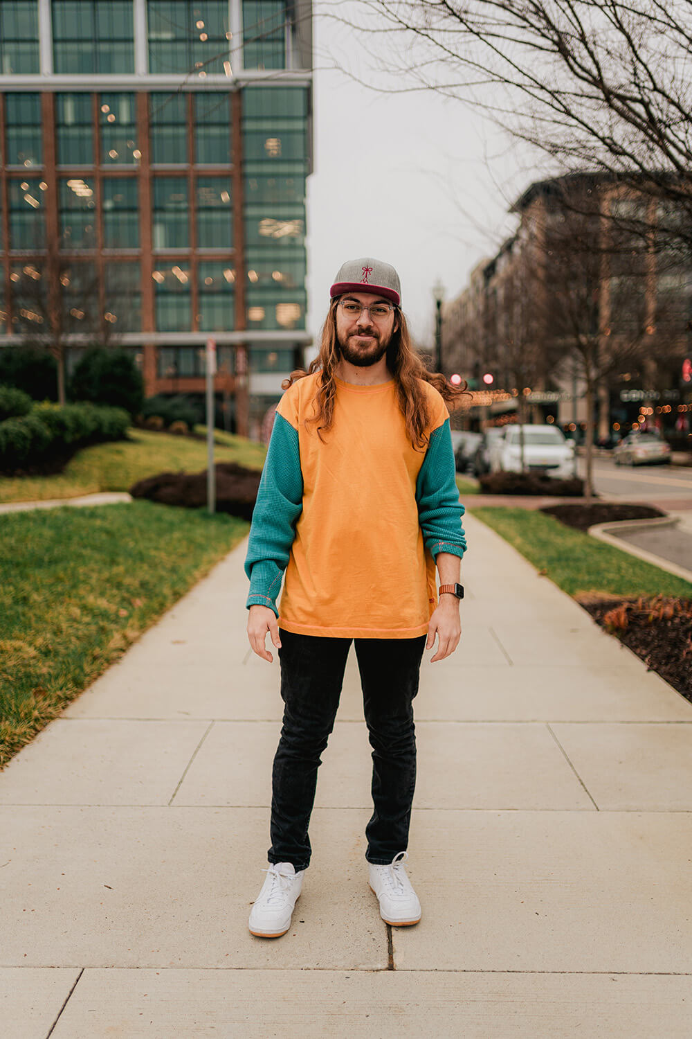 Christian Taylor rocking The Longhairs Redtail hat standing on the sidewalk