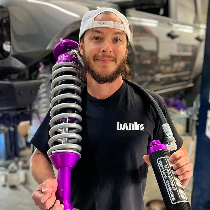Workforit Founder DMAXRYNO holding a large purple off-road racing shock