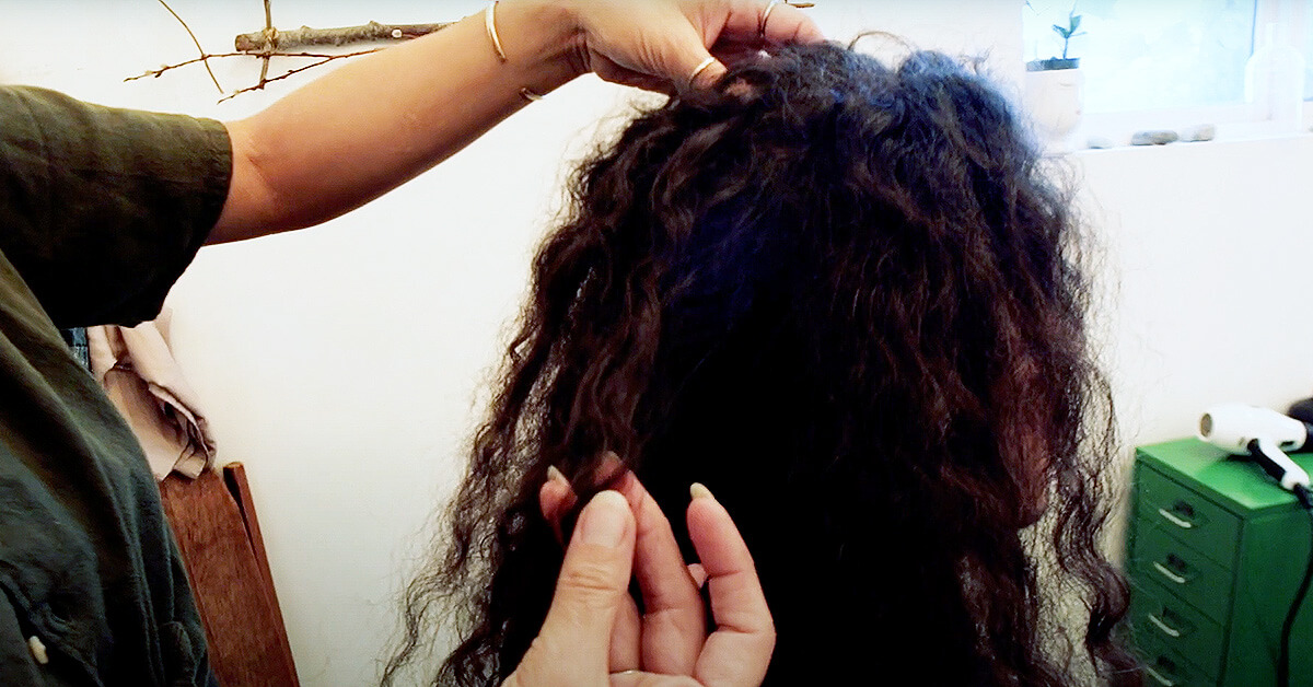 Naomi pointing out the tangles within the curly hair