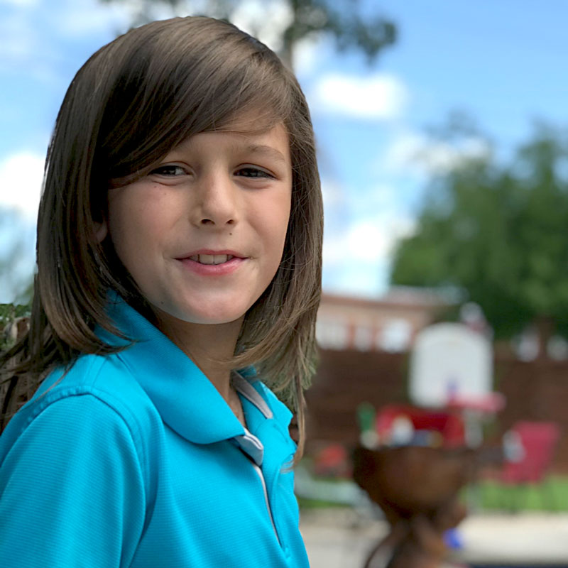 Luke with long hair and blue collar shirt, dealing with discriminatory grooming codes in texas schools