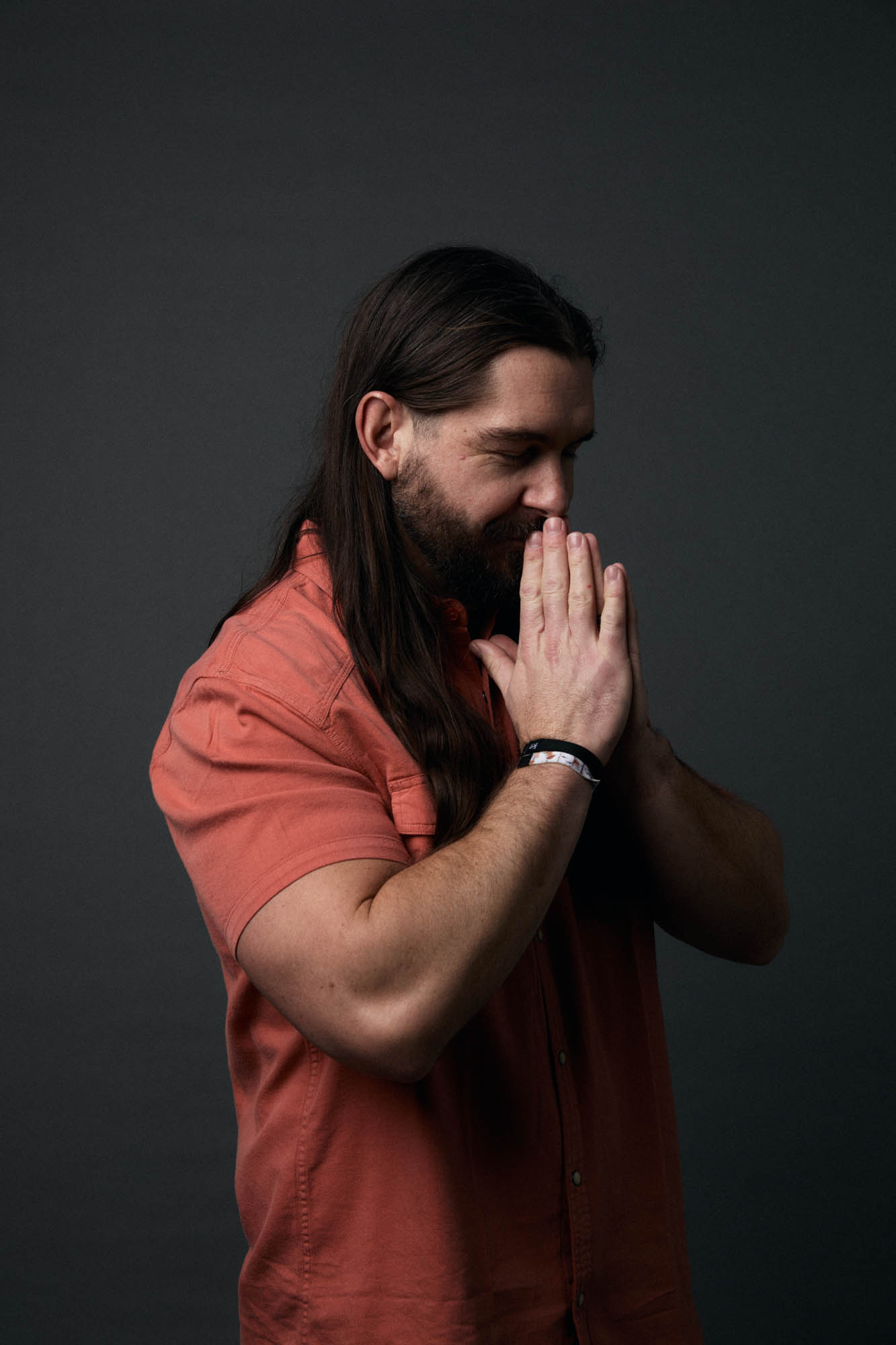 Lindsay Barto of The Longhairs with his eyes closed, hands together palms facing inward in a gesture of prayer, expressing gratitude. By Erica Joan 2024.