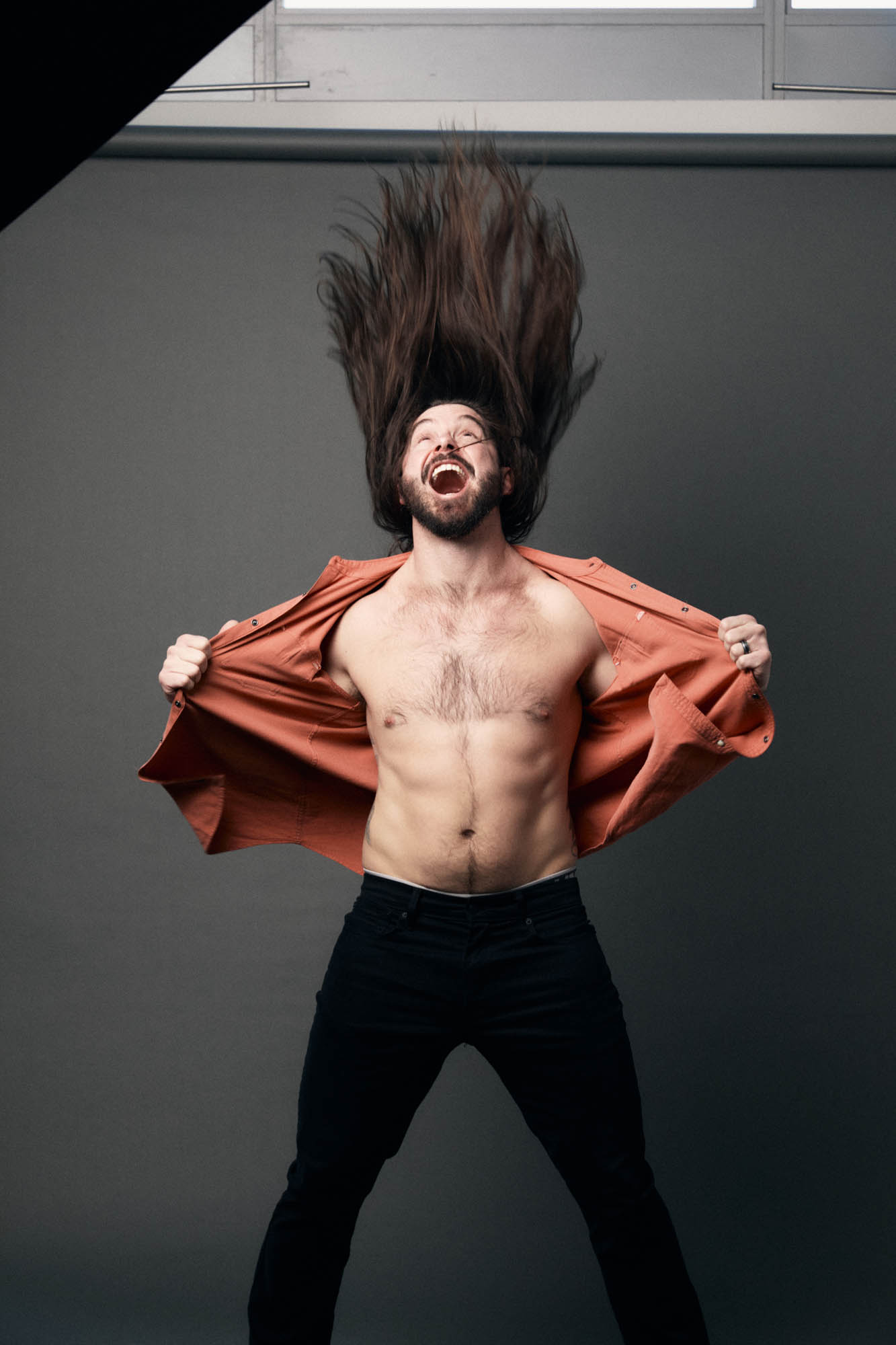Lindsay Barto, President of The Longhairs, ripping his shirt apart while hair whipping, very fit and excited. By Erica Joan 2024.