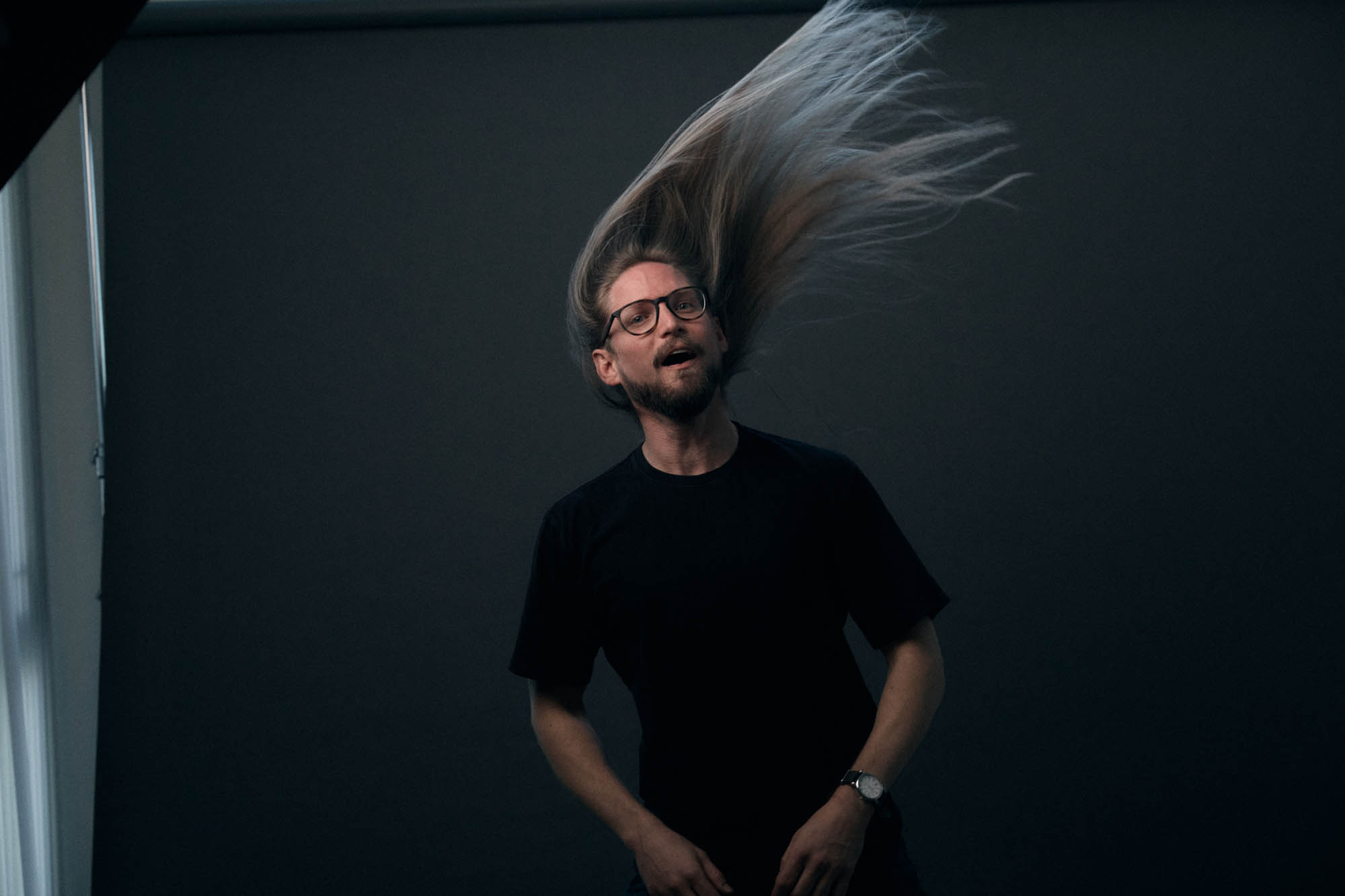 Sean Horton whipping his hair, looking at the camera. By Erica Joan 2024.