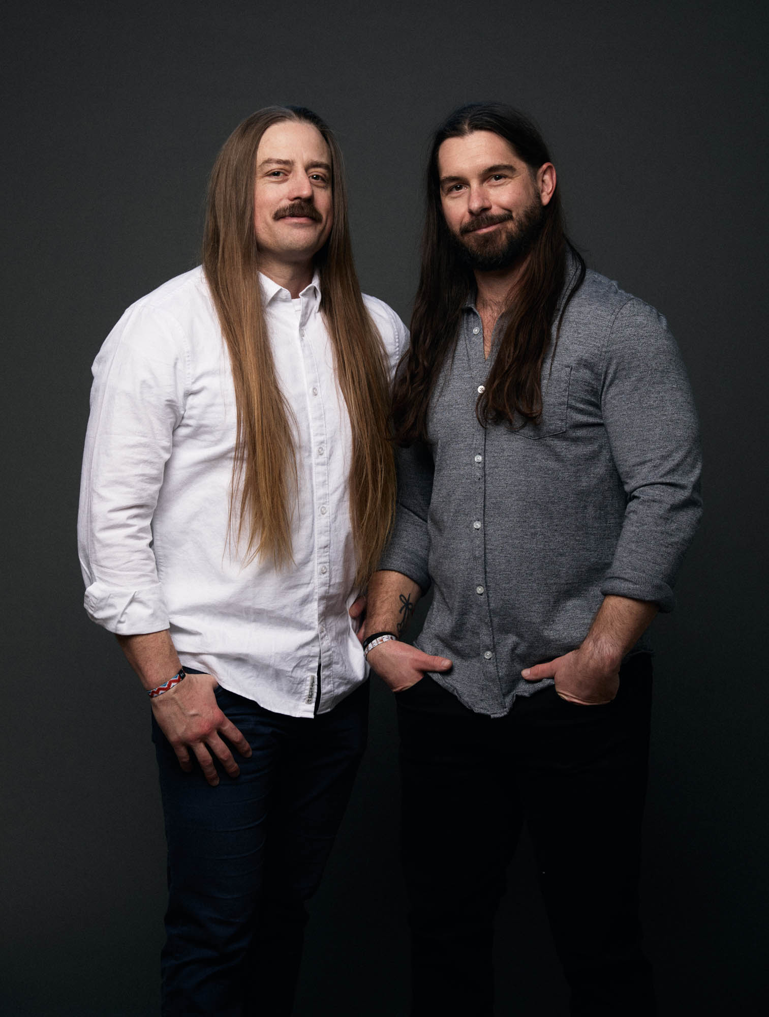 Chris Healy and Lindsay Barto, co-founders of The Longhairs, wearing button-up shirts, smiling and looking at the camera. By Erica Joan 2024.
